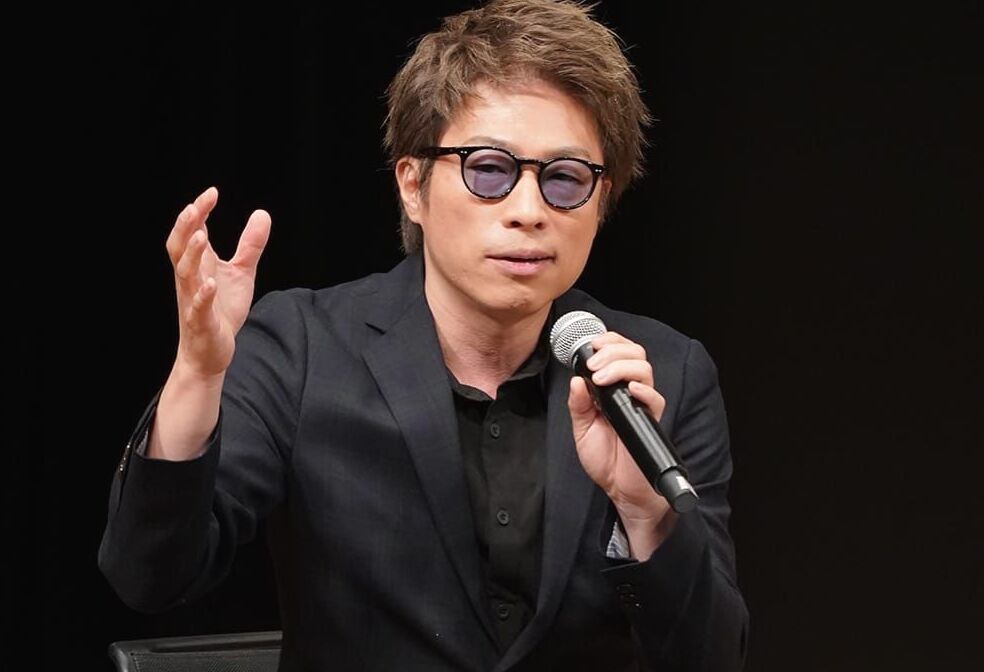 2024年3月4日の地方創生SDGs国際フォーラムで話す田村淳。内閣府地方創生推進事務局／Wikimedia Commons、CC BY 4.0。左右各20px、上下各14pxを裁ち、全体の明るさを2％上げた。『あいの里』シーズン3の劇中写真や2026年10月の収録写真ではない。